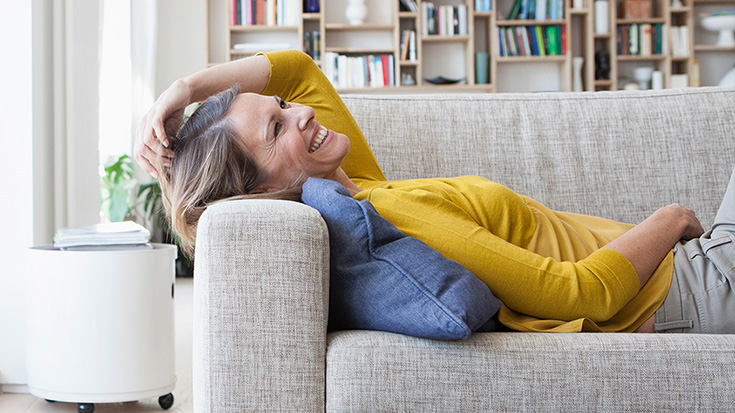 Frau liegt auf dem Sofa in heller Wohnung