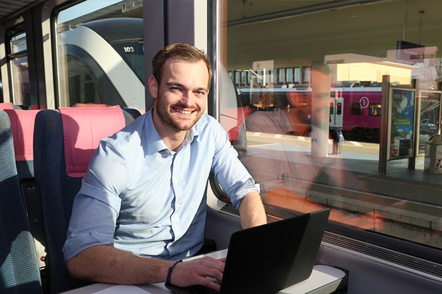Mitarbeiter im Zug am Laptop.