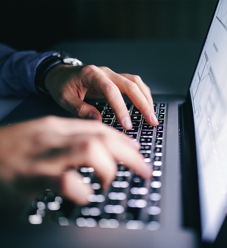 Nahaufnahme von tippenden Händen auf einen Laptop