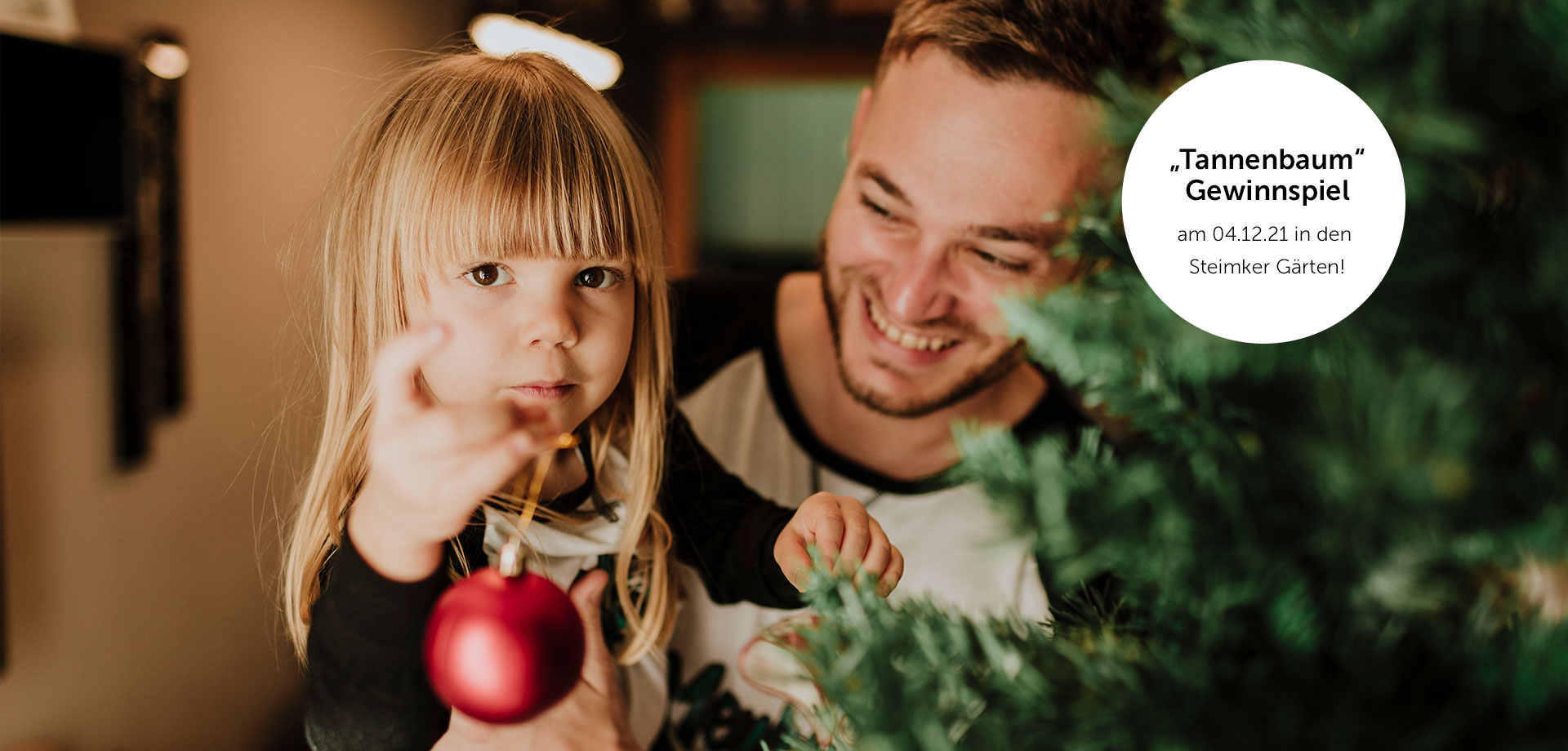 Kleines Mädchen hängt eine Weihnachtskugel auf